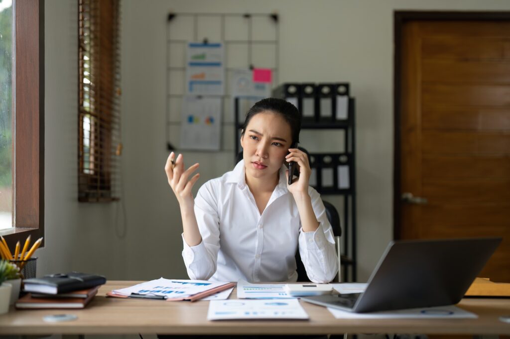 Angry, phone and stressed asian woman on a business call about tax, audit and compliance email on