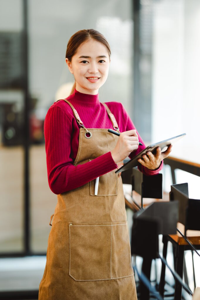 Confident small business owner holds tablet in hand and smiles cheerfully. Beautiful female staff ar