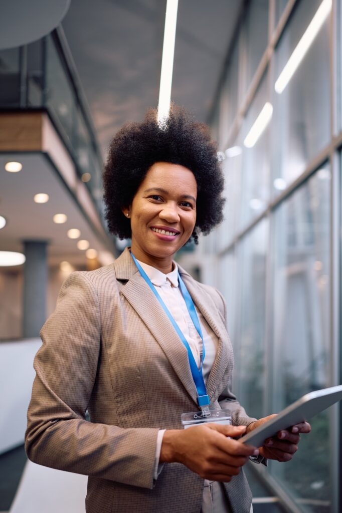 Happy black CEO using touchpad while working in the office and looking at camera.