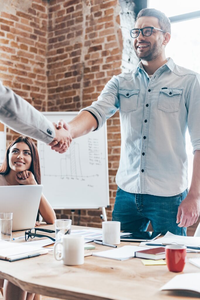 Welcome on board! Two businessmen shaking hands while standing near office table